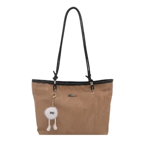 Large khaki tote bag with black handles and cute plush charm for daily commuting
