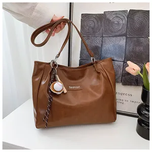 Detail of dark brown tote bag with fashion tag and creative baseball bat charm