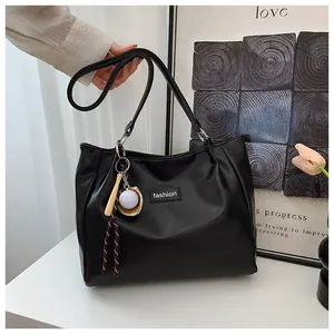 Detail of black large capacity tote bag with fashion patch and baseball charm pendant