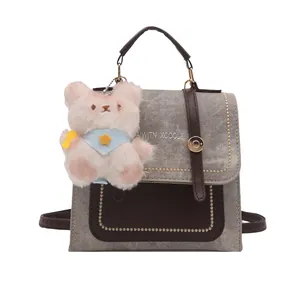 Sac à dos tendance en denim gris et cuir marron avec breloque ours et broderie