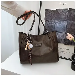 Close-up of a large coffee brown tote bag with fashion tag and baseball charm detail