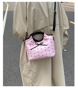 Détail du sac à bandoulière rose à nœuds avec sangle noire en style urbain