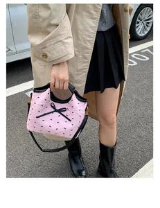 Détail d'un sac rose avec nœud noir porté en bandoulière dans un décor street style