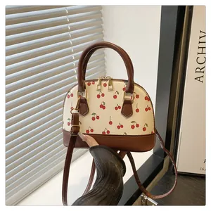 Close-up of sweet cherry print details on beige leather bag with gold-tone dual zippers