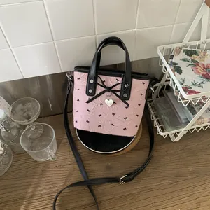 Sac à bandoulière rose avec nœuds papillon, pendentif cœur et sangle noire réglable