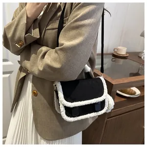 Zwarte crossbodytas met witte pluche rand en een zacht pompon-accessoire eraan