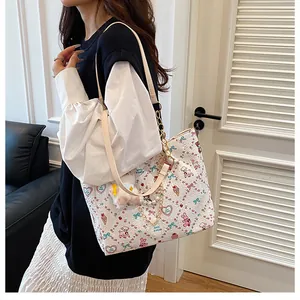 Detail of white tote bag featuring cartoon prints, pearl chain, and plush bear charm
