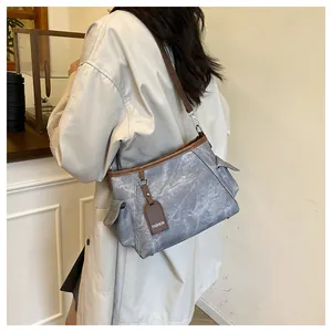 Detail of vintage gray bucket bag with brown straps and 'FASHION' tag in a cafe setting