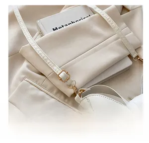 Detail of adjustable gold buckle and cream leather strap on minimalist saddle bag