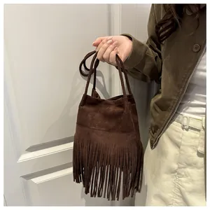 Détail du sac seau en daim marron foncé avec de longues franges et anse en corde