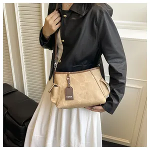 Detail view of khaki canvas crossbody bucket bag with dark brown leather piping trim