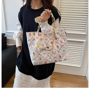 Close-up of white tote bag with cute cartoon prints, gold chain, and plush rabbit charm