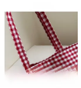 Close-up of high-quality stitching and durable strap on the red checkered canvas tote bag