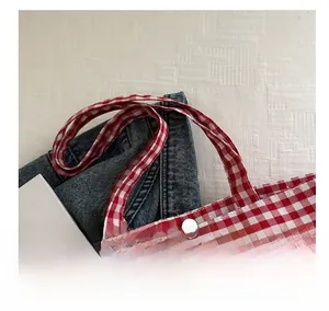 Close-up of red and white checkered canvas tote bag with a metal magnetic closure buckle