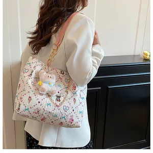 Detail of white square tote bag with colorful cartoon prints and plush cat charm