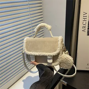 Beige suède zadeltas met witte shearling rand en een kleine portemonnee-hanger