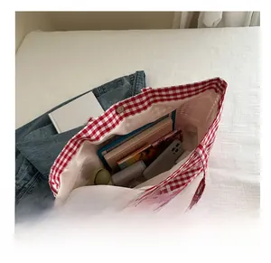 Detail showing the large capacity of a red and white checkered canvas tote bag
