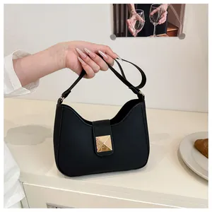 Détail d'un sac à bandoulière en cuir noir mat avec fermoir métallique doré et sangle