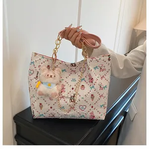 Detail of white handbag with cartoon prints, pearl chain, and plush bear charm