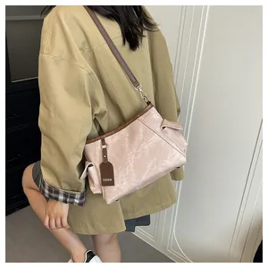 Detail of pink leather bucket bag with brown strap and silver metal hooks worn by model