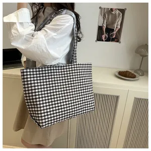 Detailed view of the black and white checkerboard canvas tote bag with shoulder straps