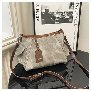 Detail of vintage canvas shoulder bag with brown leather trim and metal ring on table