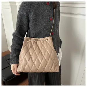 Detail of beige quilted chain bucket bag showing soft texture and gold metal strap