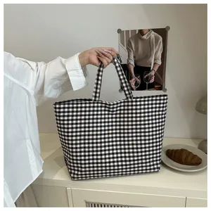 Detailed close-up of a large black and white gingham canvas tote bag held by hand