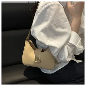 Détail d'un sac demi-lune beige orné d'une grande boucle à rivet pyramidal doré