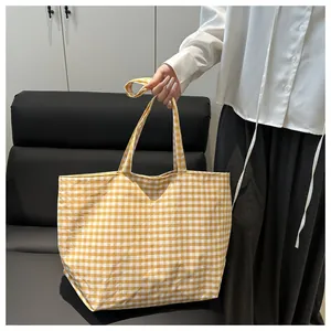 Detail of yellow gingham canvas tote bag with reinforced handles and long shoulder strap