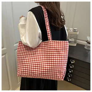 Lifestyle view of large red and white gingham canvas tote bag worn by a model