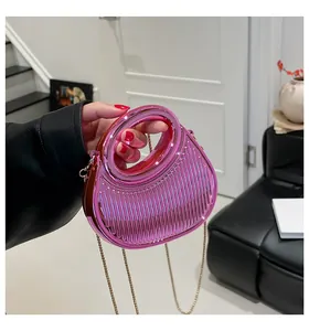 Détail du sac dumpling en acrylique rose métallisé avec texture et chaîne dorée