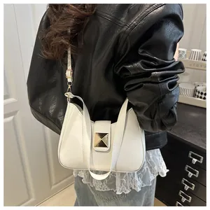 Close-up of a white leather underarm bag with a large gold square buckle on a model