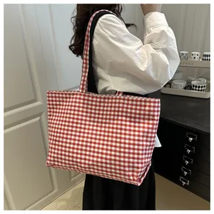 Detail view of red gingham canvas tote bag with wide shoulder strap for casual styling