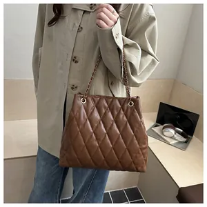 Close-up of brown quilted tote bag with gold chain straps and shiny PU leather finish
