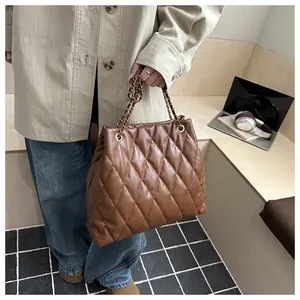 Brown quilted tote bag with chain strap styled with a beige trench coat for a chic look
