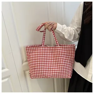 Close-up of red and white checkered canvas tote bag with wide fabric handle detail