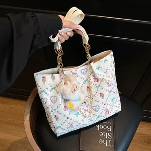 White square tote bag with colorful cartoon prints, chain strap, and plush rabbit charm