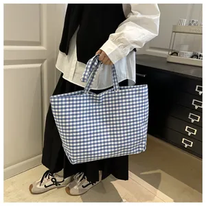 Detail view of large blue and white checkered canvas tote bag with dual handles