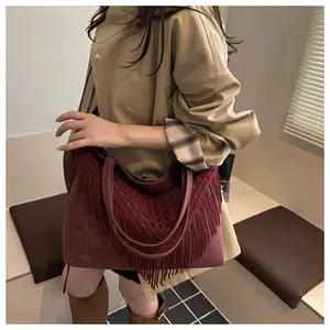 Vue latérale d'un grand sac cabas bohème bordeaux à franges porté par un mannequin