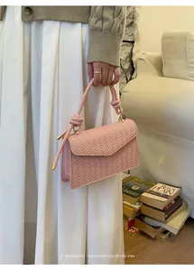 Detail of pink woven texture handbag with twisted handle and gold hardware on model