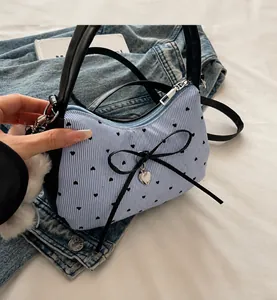 Close-up of contrast stripe mini bag with large black leather bow and silver heart charm