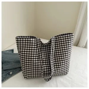 Detail of black and white gingham canvas tote bag with wide straps on white background