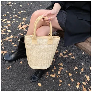 Close-up of woven straw bucket bag with herringbone texture and fabric handles
