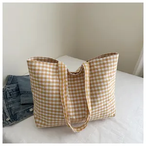 Close-up of yellow and white checkered canvas tote bag with wide shoulder strap details