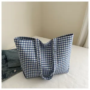 Close-up of blue and white gingham canvas tote bag on a neutral fabric background