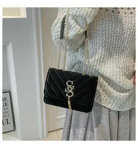 Detail of black velvet crossbody bag featuring gold tassel and V-quilted texture