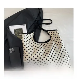 Close-up of a stylish white tote bag with black polka dots and thin black straps