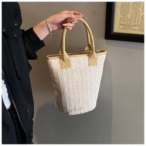 Detail of hand-woven straw tote bag featuring beige chevron pattern and yellow handles