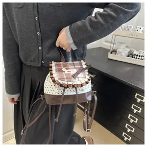 Détail d'un mini sac à dos à carreaux avec patch cerise, imprimé étoiles et bords volantés